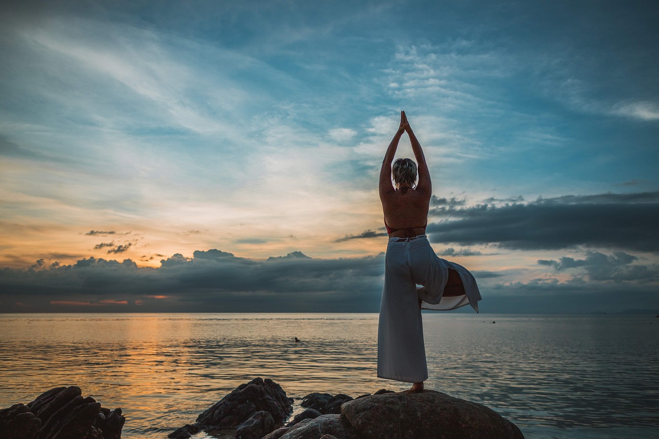 Woman doing yoga at a beach during sunset