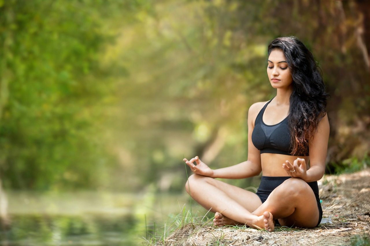 Woman meditating on a riverbank in a forest